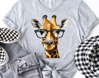 Op de afbeelding: Een grijs T-shirt met een afbeelding van een giraffe die een bril draagt. De giraffe is bruin en geel met zwarte vlekken. De bril is zwart.