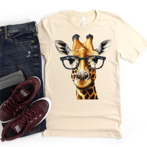 May include: A beige t-shirt with a graphic of a giraffe wearing black-rimmed glasses. The giraffe has a brown and yellow patterned coat.