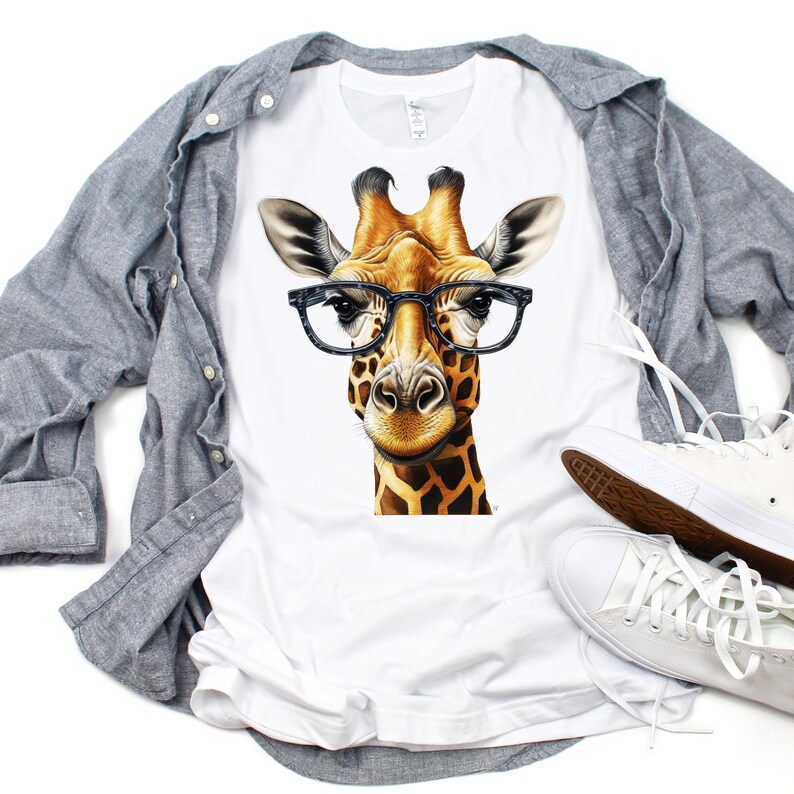 May include: White t-shirt with a graphic of a giraffe wearing black-rimmed glasses. The giraffe has a brown and yellow patterned coat.