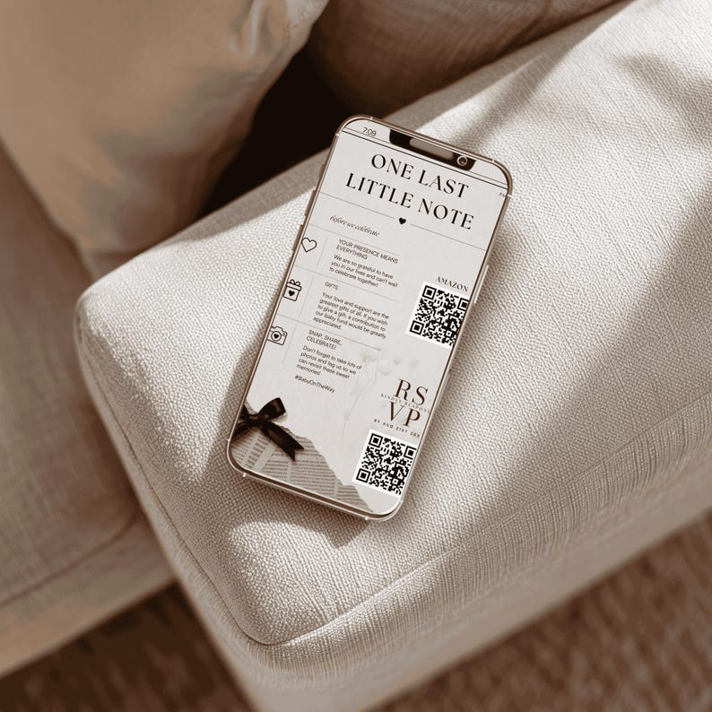 May include: A smartphone displaying a wedding RSVP note with the text "ONE LAST LITTLE NOTE". The note includes icons, QR codes, and the words "RSVP" and "Amazon". A black bow adorns the bottom of the phone.