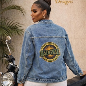 Puede incluir: Chaqueta vaquera azul claro con un parche circular "BADGYAL" en la espalda. La chaqueta se lleva sobre unos pantalones cortos blancos. El fondo presenta una motocicleta y el texto "TC LUXE Designs".