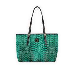 May include: A green tote bag with a scale pattern. The bag has black handles and trim, with gold-colored hardware. The bag has a small gold-colored emblem that says "LUXE".