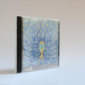 May include: A CD case with a blue and yellow illustration of a person with outstretched arms. The background is a blue and yellow pattern of dots. The text "Spread it" and "O'Connor" is visible at the bottom of the case.
