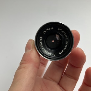 Puede incluir: Una taza de cer&aacute;mica blanca con un asa negra y el texto "But First, Coffee" en negro y negrita. La taza est&aacute; sobre una superficie blanca.