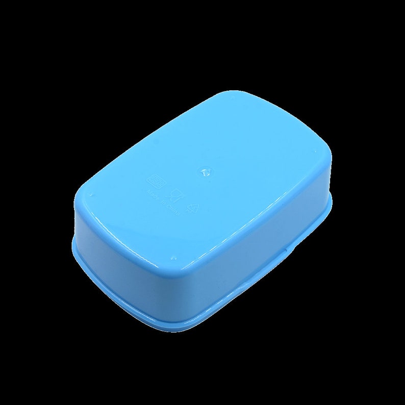 May include: A light blue plastic lunch box with a slightly rounded rectangular shape. The lunch box has a smooth surface and a small, raised area on the top.