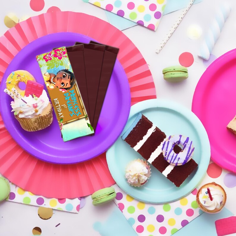 May include: A colorful birthday party favor with a Moana theme. The favor is a chocolate bar wrapper with a picture of Moana and the text "Moana's 1st Birthday".
