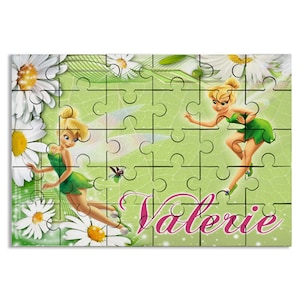 May include: A green and white jigsaw puzzle featuring Tinkerbell, a fairy with green wings and a green dress, on a green background with white daisies. The puzzle is personalized with the name "Valerie" in pink letters.