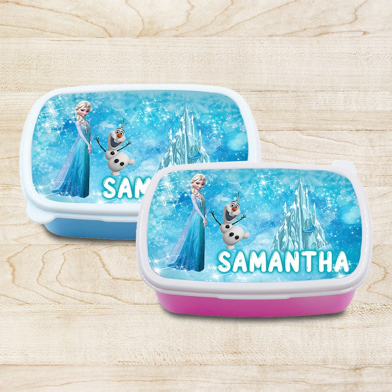 May include: Two blue and pink lunchboxes with a Frozen theme. The lunchboxes feature Elsa and Olaf from the movie Frozen. The lunchboxes have a white rim and a blue and white design with a castle and snowflakes. The blue lunchbox has the name "SAM" on it and the pink lunchbox has the name "SAMANTHA" on it.