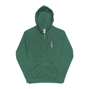 May include: A forest green zip-up hoodie with a drawstring hood and a front zipper. The hoodie features a stylized lightning bolt design in shades of blue and gray on the left chest. The hoodie is made of a soft material.