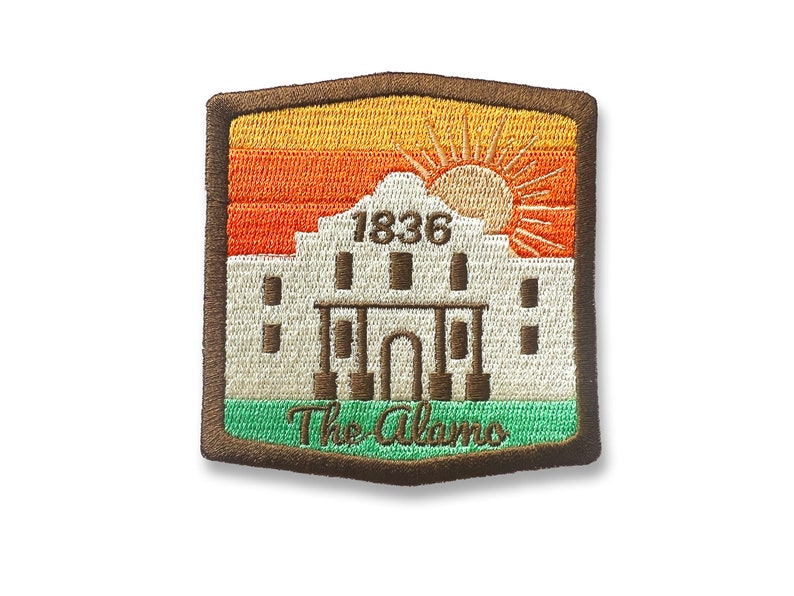 May include: An embroidered patch featuring a sunset scene with a white building and the text "1836 The Alamo".