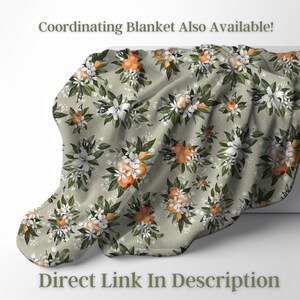 May include: A soft, floral blanket with a repeating pattern of orange fruit and white flowers with green leaves on a light green background. The text "Coordinating Blanket Also Available!" and "Direct Link In Description" are visible.