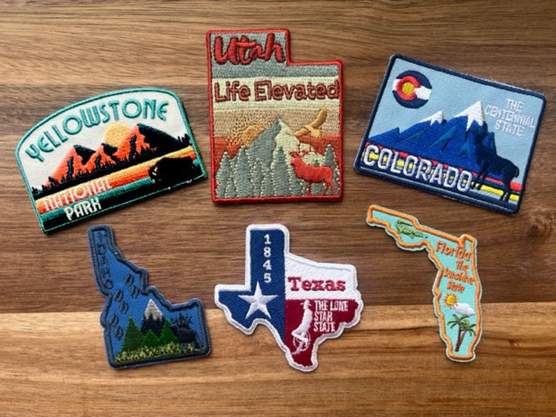 May include: A collection of embroidered patches featuring state and national park designs. The patches are colorful and feature various landscapes, including mountains, forests, and rivers. The patches are perfect for adding a touch of personality to backpacks, jackets, or other items.