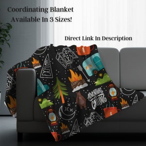 May include: A black blanket with a camping theme, featuring illustrations of campfires, trees, a bear, and a camper. The blanket has the text "Adventure is Calling" and "Explore". Available in 3 sizes.