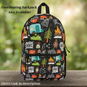 May include: Black backpack with a camping-themed pattern. The design includes illustrations of a camper, campfire, bear, trees, and the words "Adventure is Calling". The backpack has a black handle and zipper.