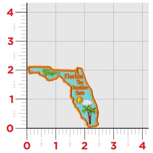 May include: An embroidered patch shaped like the state of Florida. The patch is orange and blue with the text "Florida The Sunshine State" and a small image of a palm tree, sun, and cloud.