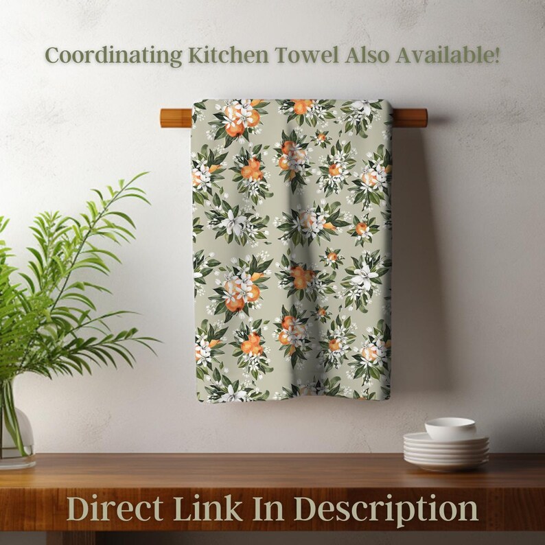 May include: A kitchen towel with a floral pattern of orange blossoms and white flowers on a light green background. The towel is hanging on a wooden rod. The text "Coordinating Kitchen Towel Also Available!" and "Direct Link In Description" are visible.