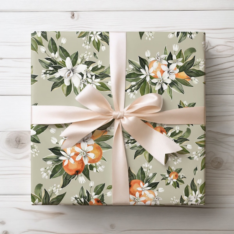 May include: A gift wrapped in green and white floral wrapping paper with a white bow. The paper features a repeating pattern of orange blossoms and oranges.
