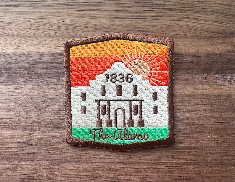 May include: A brown, orange, and green embroidered patch with a white silhouette of the Alamo, the text "1836", and the text "The Alamo".