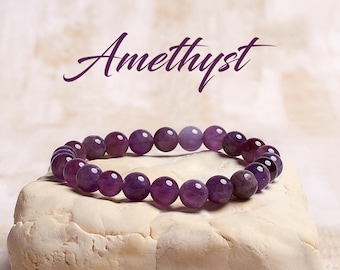 May include: Amethyst bracelet made with purple gemstone beads. The bracelet is on a light beige surface.