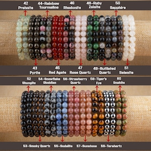 Puede incluir: Una colecci&oacute;n de 10 pulseras de piedras preciosas, cada una con un tipo de piedra diferente. Las pulseras est&aacute;n dispuestas en dos filas, la fila superior muestra pulseras hechas de prehnita, turmalina, rodonita, zoisita y zafiro. La fila inferior muestra pulseras hechas de pirita, &aacute;gata roja, cuarzo rosa, cuarzo rutilado, selenita, shungita, obsidiana, cuarzo fresa, ojo de tigre, unakita, cuarzo ahumado, sodalita, piedra de sol y terahertz.