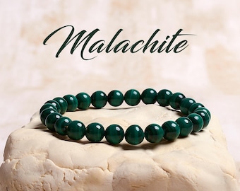 May include: A green malachite gemstone bracelet with round beads. The bracelet is on a white surface. Malachite.