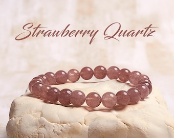 May include: A bracelet made of round, strawberry quartz beads. The beads are a translucent pinkish-red color. The bracelet is displayed on a textured, off-white surface. The words "Strawberry Quartz" are written above the bracelet.