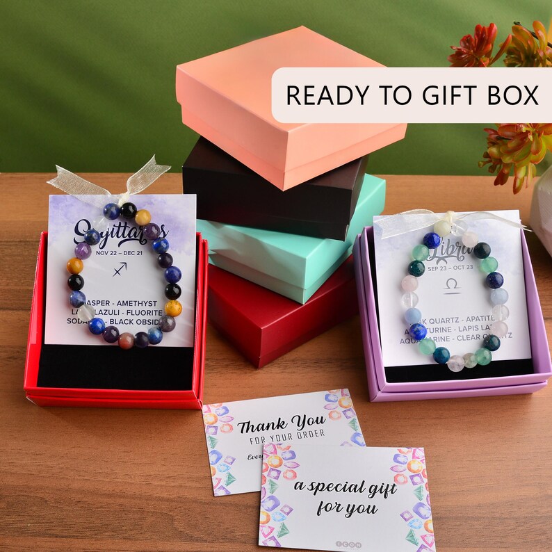 May include: A collection of colorful gift boxes, including pink, black, teal, and red, with bracelets and cards. The bracelets feature various gemstones. The cards say "Thank You" and "a special gift for you". The text "READY TO GIFT BOX" is visible.