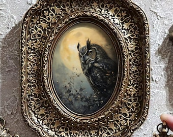 May include: Five ornate gold-toned frames containing miniature paintings of owls perched against a full moon. The frames feature intricate scrollwork and filigree details. Four frames are mounted, while one smaller oval frame is held by hand.