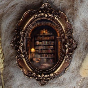 May include: An oval-shaped, ornate, bronze-colored frame with a miniature library scene inside. The library features bookshelves filled with books, a reading lamp, and a cozy armchair. The frame is set against a soft, textured background.