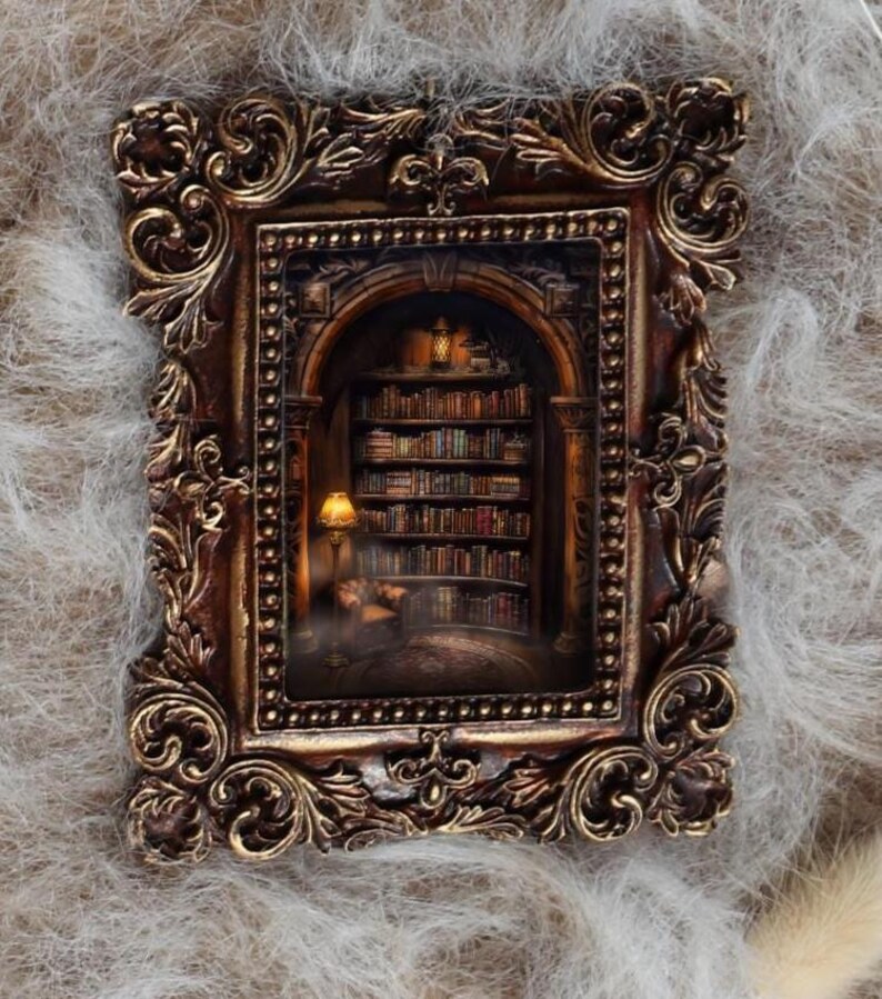 May include: A detailed, ornate brown picture frame with gold accents. Inside, a miniature library scene is illuminated by a warm lamp, with bookshelves and a person reading. The frame is set against a soft, textured background.