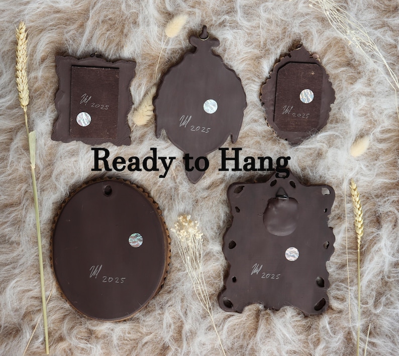 May include: Five brown decorative wall hangings of various shapes, including a square, oval, and ornate designs. Each piece has a textured surface and a small, round magnet. The text "Ready to Hang" is displayed in the image.
