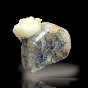 May include: A clear quartz crystal with a cloudy, grey and white appearance. The crystal has a unique, irregular shape and is partially covered in a white, opaque mineral.