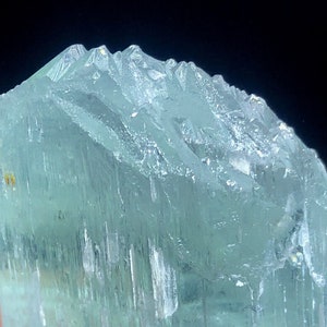 May include: A large, light blue aquamarine crystal with a smooth, glassy surface. The crystal has a slightly cloudy appearance and is translucent.
