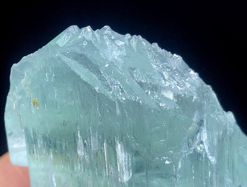 May include: A large, light blue aquamarine crystal with a smooth, glassy surface. The crystal has a slightly cloudy appearance and is translucent.