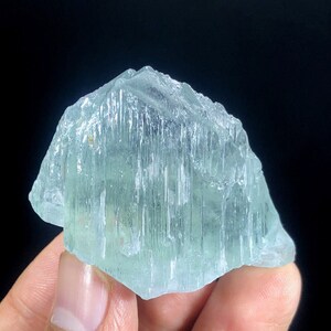 May include: A large, light blue aquamarine crystal with striations and a translucent appearance.