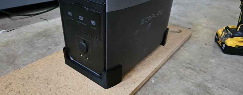 Pu&ograve; includere: Una stazione di alimentazione EcoFlow nera e grigia con pi&ugrave; porte e il logo EcoFlow. La stazione di alimentazione &egrave; su una tavola di legno marrone chiaro. Un trapano giallo e nero &egrave; sullo sfondo.