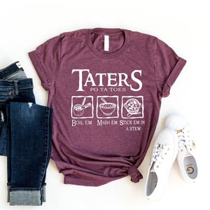 May include: A maroon t-shirt with the text "Taters Po Ta Toes" and a graphic of three different ways to prepare potatoes: boil, mash, and stick in a stew. The shirt is paired with blue jeans and white sneakers.