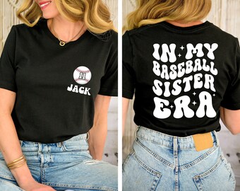 May include: Black t-shirt with a white baseball graphic and the text "JACK" on the front. The back of the shirt has white text that reads "IN MY BASEBALL SISTER ERA" in a retro font.