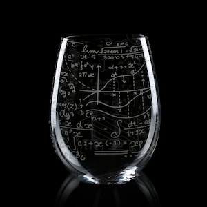 May include: A clear glass wine glass with a white design of mathematical equations and formulas. The design includes a graph, integrals, and other mathematical symbols.
