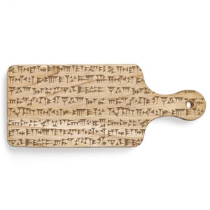 Puede incluir: Tabla de cortar rectangular de madera clara con asa y agujero para colgar. La superficie está cubierta de marcas grabadas en marrón oscuro. El asa es redondeada. Ideal para la cocina.