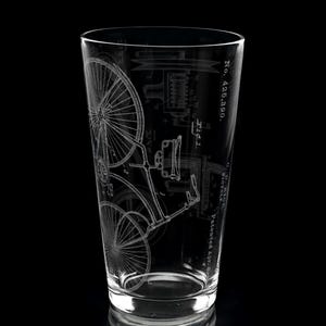 May include: A clear glass pint glass with an etched design of a vintage bicycle patent. The patent number is No. 425,390. The design is in black and white.
