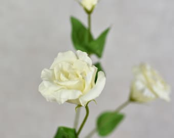 May include: A bouquet of three white lisianthus flowers with green stems and leaves.