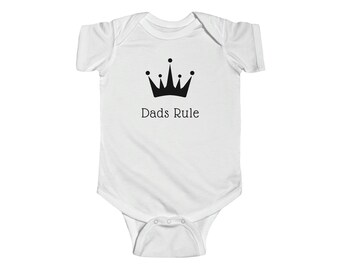May include: White baby grow with a black crown and the text "Dads Rule" printed on the front.