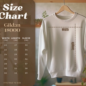 May include: Size chart for Gildan 18000 sweatshirts, showing width, length, and sleeve measurements in inches for sizes S through 4XL.  The chart is displayed on a brown background with a white sweatshirt hanging on a wooden hanger.