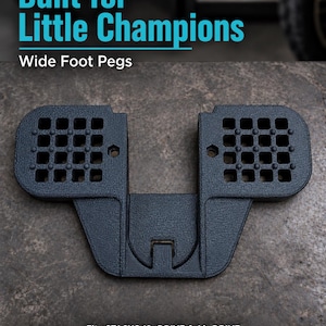 May include: A black textured wide foot peg accessory for a balance bike. The text reads: Built for Little Champions, Wide Foot Pegs, Fits STACYC 12eDRIVE & 16eDRIVE, Not compatible with Elite models. The part features a grid pattern.