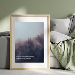 Puede incluir: Una impresión enmarcada que presenta una escena de bosque brumoso con árboles en tonos morados y grises. La impresión incluye el texto: "Ninguna medida de tiempo contigo será lo suficientemente larga, pero empecemos con siempre."