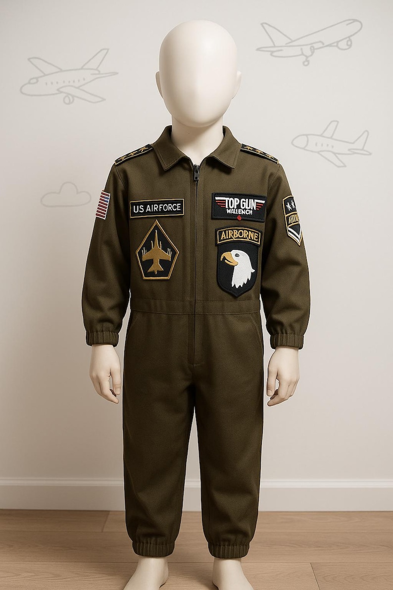 May include: Olive green children's jumpsuit with multiple patches, including "US AIRFORCE", "TOP GUN", and "AIRBORNE". The costume features a zipper closure and long sleeves. The patches include an American flag and military insignia.