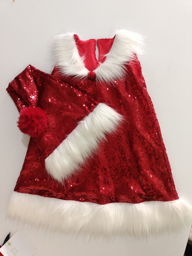 May include: Red sequin Christmas dress with white faux fur trim and a matching red sequin Santa hat with a white faux fur brim and a red pom pom.