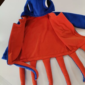 May include: Blue and orange octopus costume with a hood and large eyes. The costume is open to show the orange fleece lining.