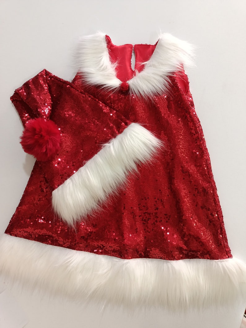May include: Red sequined dress with white faux fur trim and a matching red sequined Santa hat with a white pom-pom.